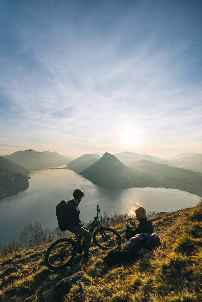 マウンテンバイカーは草の多い山の尾根でリラックス - ticino canton mountain lake lugano lake ストックフォトと画像