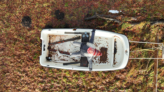 Aerial drone shot of laughing woman sitting in boat on land