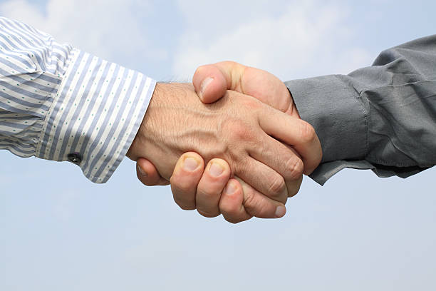 Two hands handshake on sky background stock photo