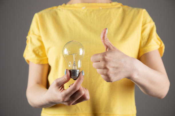 istock girl holding a light bulb and showing thumb up 1361422412
