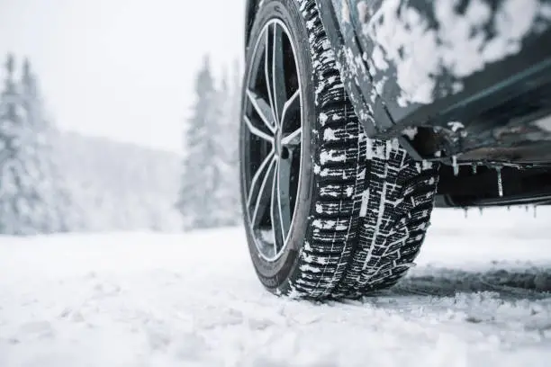 Close up of black car tyre covered with snow on a snowy road
