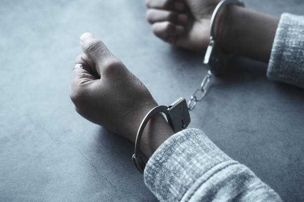 istock man's hand with handcuff on black background. 1361441295