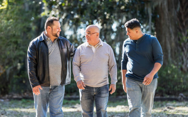 istock Senior Hispanic man with adults sons walking in park 1361443455