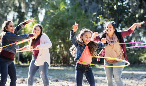 niña hispana con familia en el parque jugando con aros - hooping fotografías e imágenes de stock