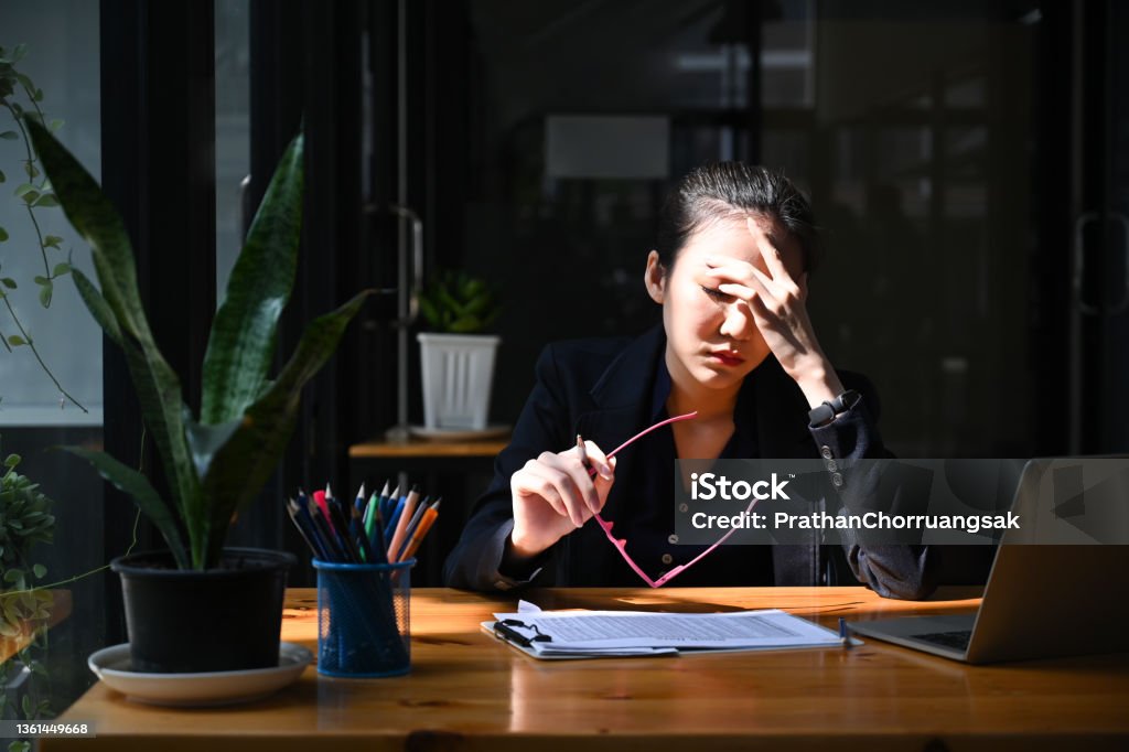 Overworked businesswoman take off glasses and massaging her head. Emotional Stress Stock Photo