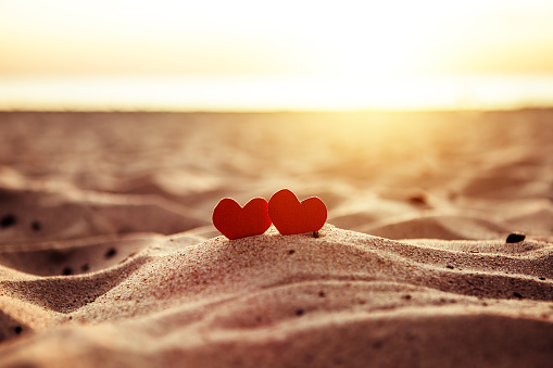 Toned Photo of Two Red Hearts in the Sand at the Evening Beach