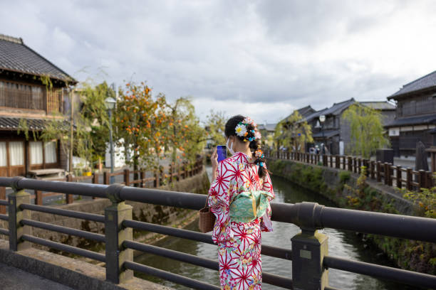 Teenage girl in kimono taking pictures in Japanese village stock photo