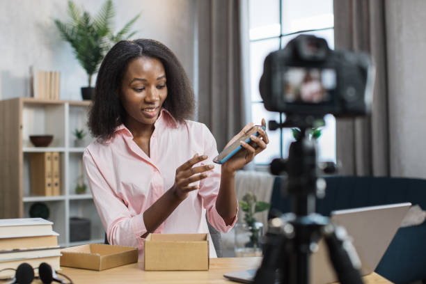 istock Woman filming video while opening box with new mobile 1361457027