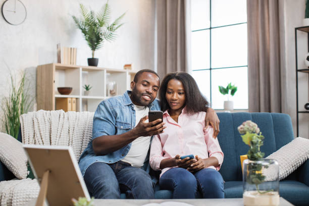 istock Loving couple sitting on couch and using smartphones 1361457035