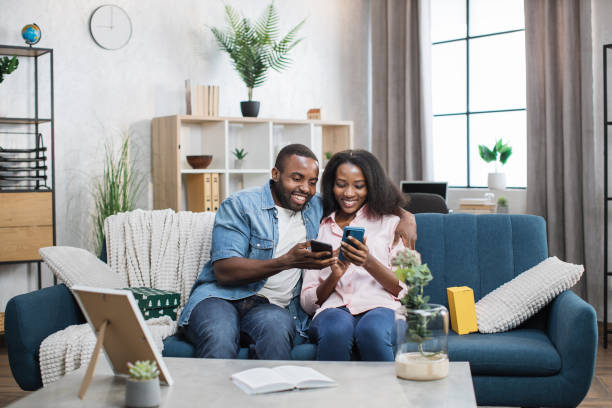 istock Happy couple relaxing on sofa with smartphones in hands 1361457042