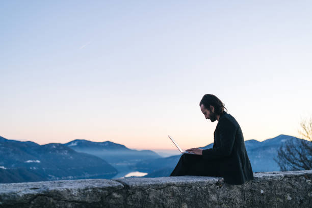istock Businessman relaxes on mountain ridge at sunrise 1361458977