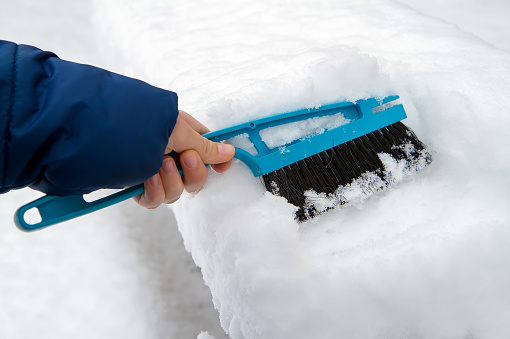 A snow brush in a person's hand. Snow removal with a snow cleaning brush.