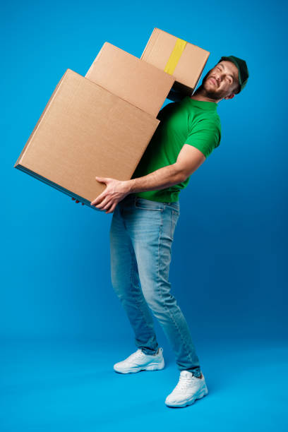 istock Delivery man with huge pile of boxes against blue background 1361462282