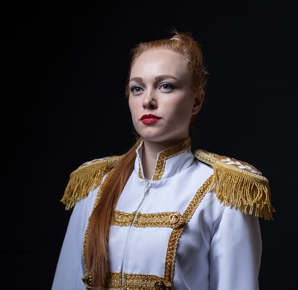 a beautiful girl poses in an officer's costume, with gold shoulder straps, on a black background