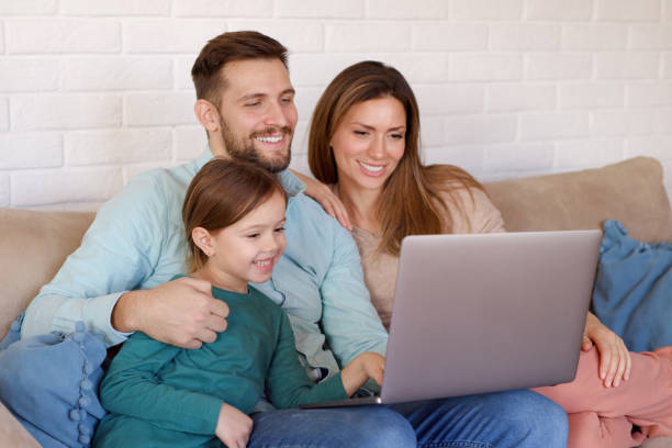 istock Smiling family relaxing at home and using laptop together 1361467549