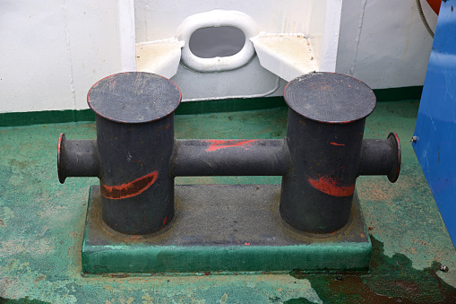 Metal bollard against the background of the hawse in the bulwark of the river ferry.