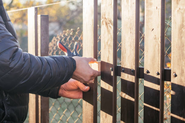 istock Hands of carpenter attaching wooden plank to metal construction for checking, reconstructing fence in sunny autumn day. 1361469211