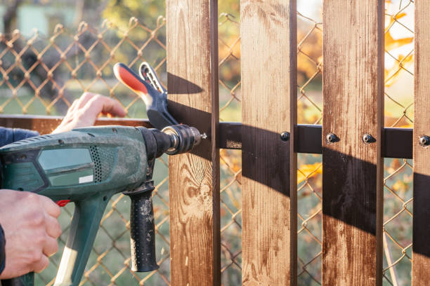 hand of carpenter hold electric drill for making hole into wooden plank to metal construction for reconstructing fence. - reconstructing imagens e fotografias de stock