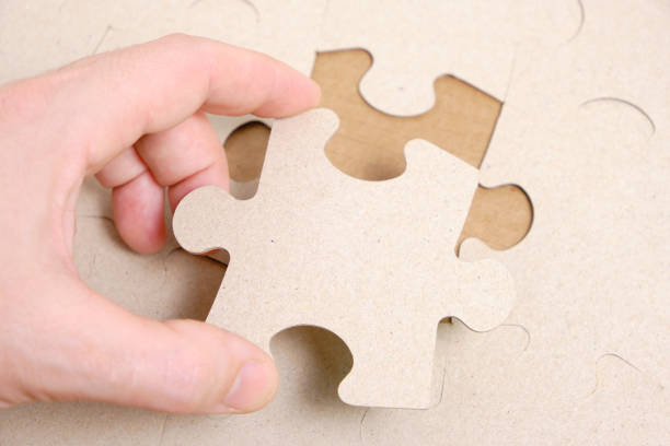 istock Man's hand attaches the missing piece of the puzzle. 1361469574