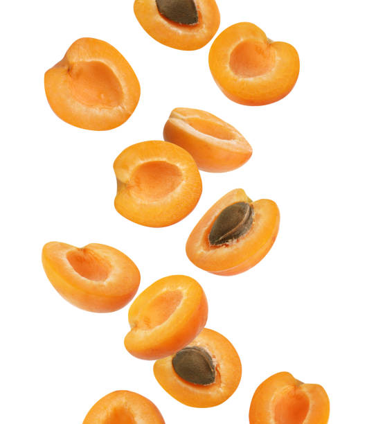 istock Cut ripe apricots falling on white background 1361470466