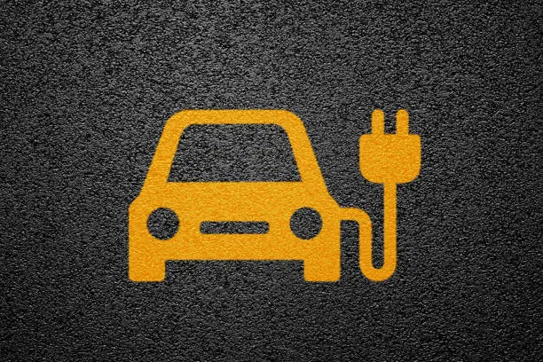 Yellow electric vehicle charging station symbol on asphalt