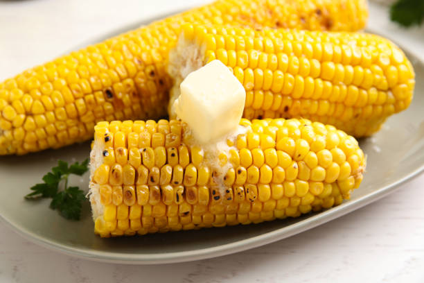 istock Fresh grilled corn cobs with butter on white wooden table, closeup 1361473506