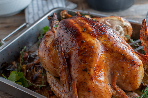 Homemade traditional roasted turkey served in a pan on kitchen table. Closeup view
