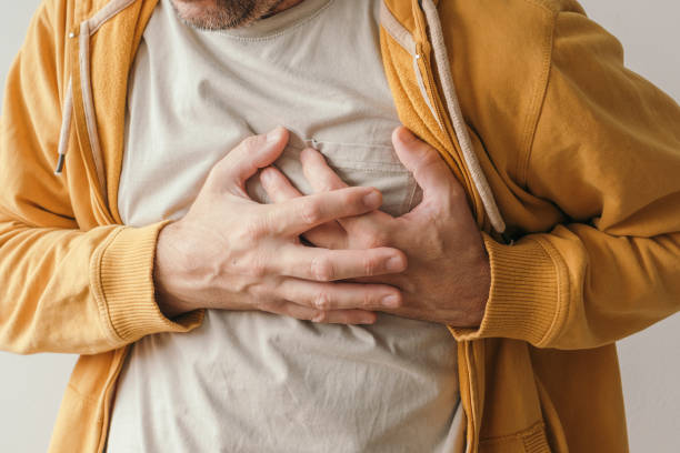 Aching heart and heart attack, adult male with painful grimace pressing the upper abdomen stock photo