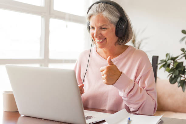 istock Happy middle aged online course student in headphones learning watching webinar on laptop 1361489667