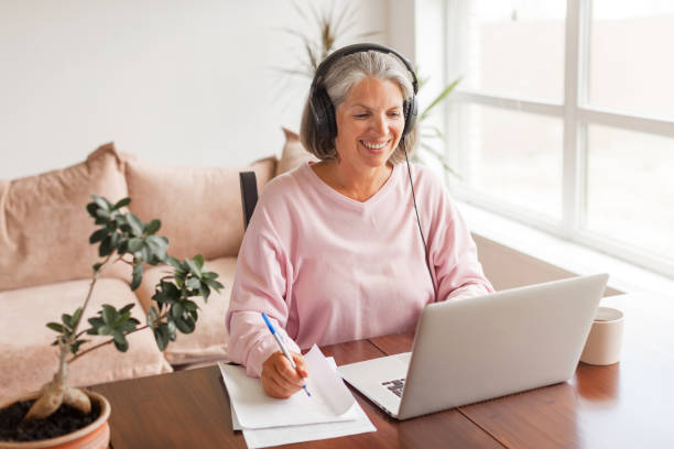istock Middle aged businesswoman using earphone while sitting behind her laptop 1361489671