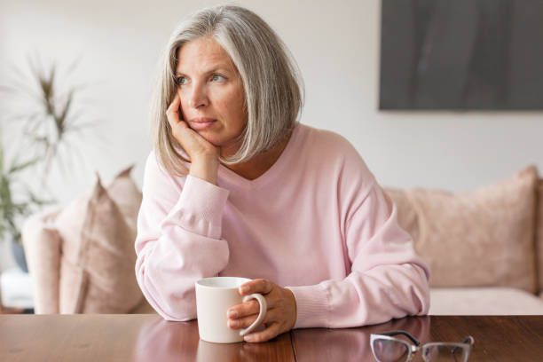 istock Sad pensive middle age woman looking down depressed sitting on the sofa 1361489688