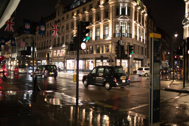 Regent Street in London after rain with cabs driving by illuminated buildings at night