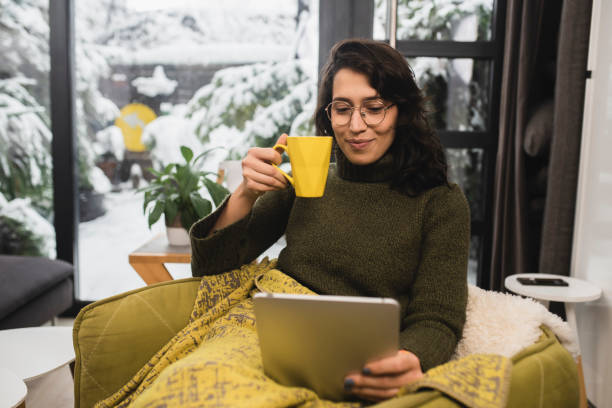 istock Happy young woman enjoying coffee under the blanket and using tablet 1361491905