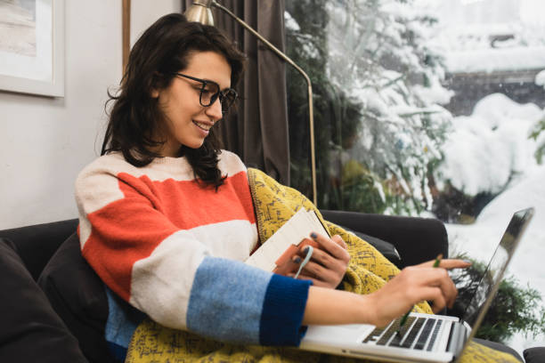 istock Happy student enjoying on the sofa and studying online 1361491920