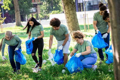 Multiethnic group of volunteers with garbage bags cleaning city park.