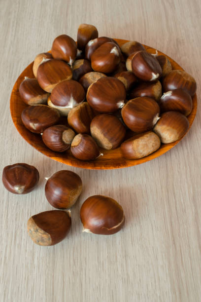 istock Ripe chestnuts on a plate on wooden background 1361499292