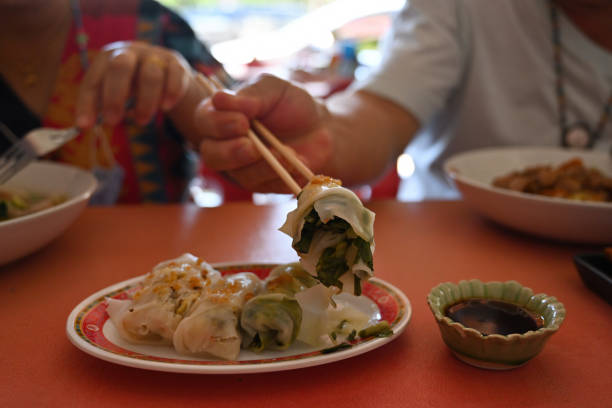 istock Cropped image of a man using a chopstick tong a fresh spring roll at the lunch table. 1361501655