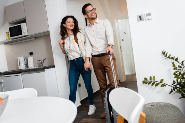istock Smiling couple with suitcase arriving in apartment. 1361501691