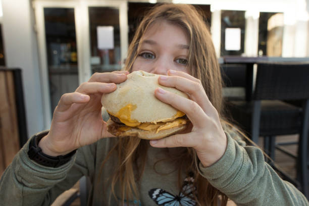 istock beautiful young eating a big burger with cheese 1361501714