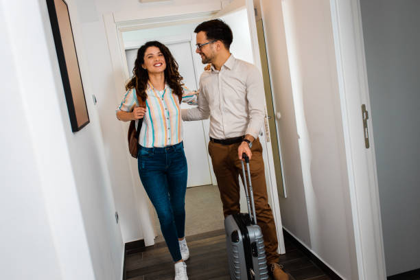 istock Smiling couple with suitcase arriving in apartment. 1361501912