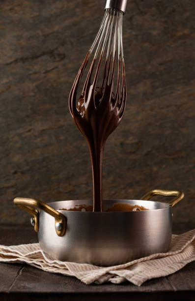 istock Liquid chocolate cream pouring from a whisk into a ladle. 1361510230