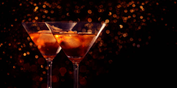 dos gafas de martini frente al fondo rojo bokeh. bebida cóctel de lujo en bar restaurante con luces nocturnas borrosas. fiesta de celebración de bebidas con clase para año nuevo, navidad, san valentín. - martini fotografías e imágenes de stock