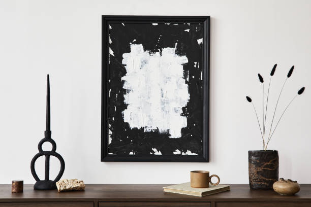 istock Stylish living room interior composition with mock up poster frame, brown wooden commode and small home decorations. White wall. Copy space. Template. 1361516005