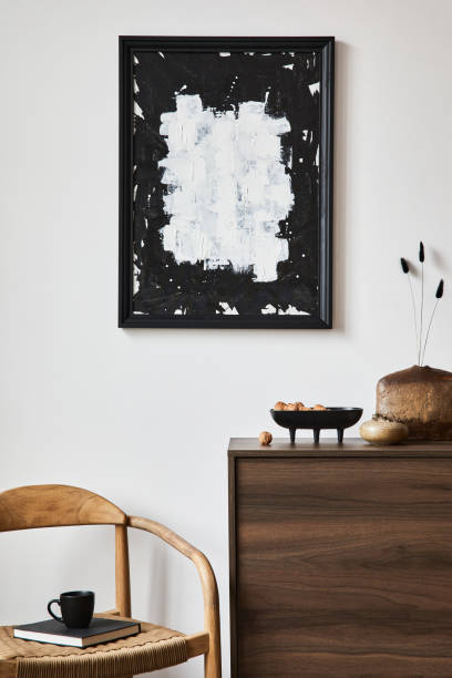 istock Stylish living room interior composition with mock up poster frame, brown wooden commode, armchair and small home decorations. White wall. Copy space. Template. 