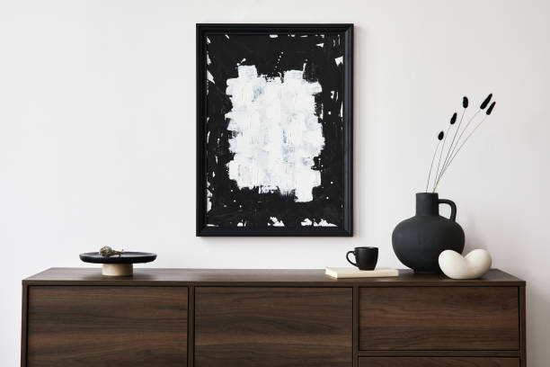 istock Minimalistic composition of creative living room interior with mock up poster frame and stylish small personal accessories on wooden commode. Copy space. Template. Real photo.