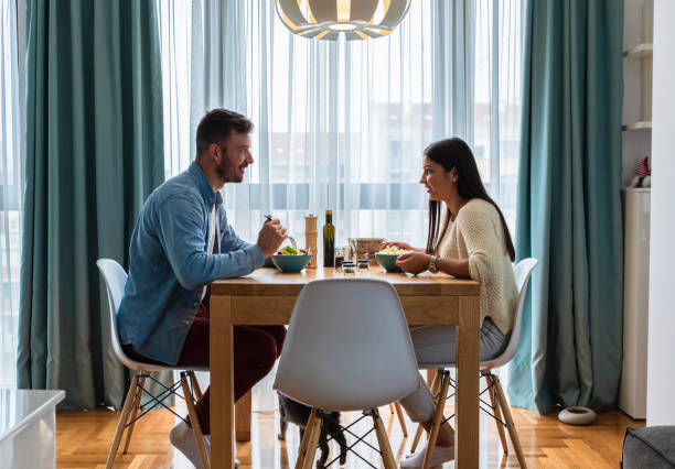 istock Young couple eating salad while sitting at a table at home. 1361523608