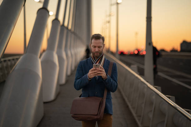 Businessman in the city texting on sunset