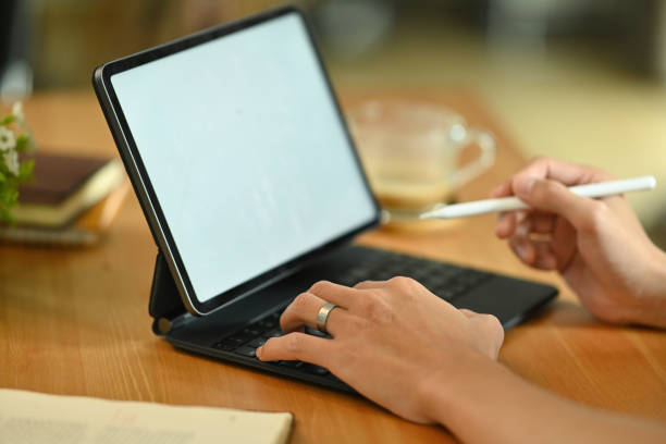 istock Cropped image of a young freelance man using a white blank screen digital tablet and stylus pen at the wooden working desk. 1361529560