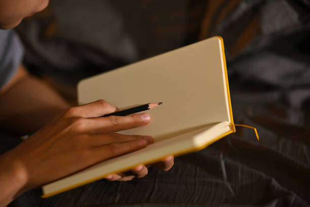 istock Close-up image of a young man taking notes while laying on the bed. 1361531743