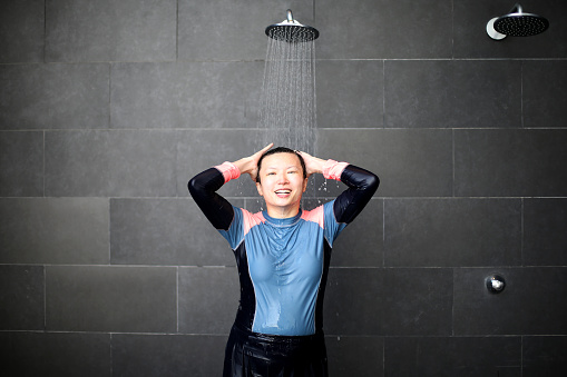 An Asian woman is rinsing herself after enjoying swimming.